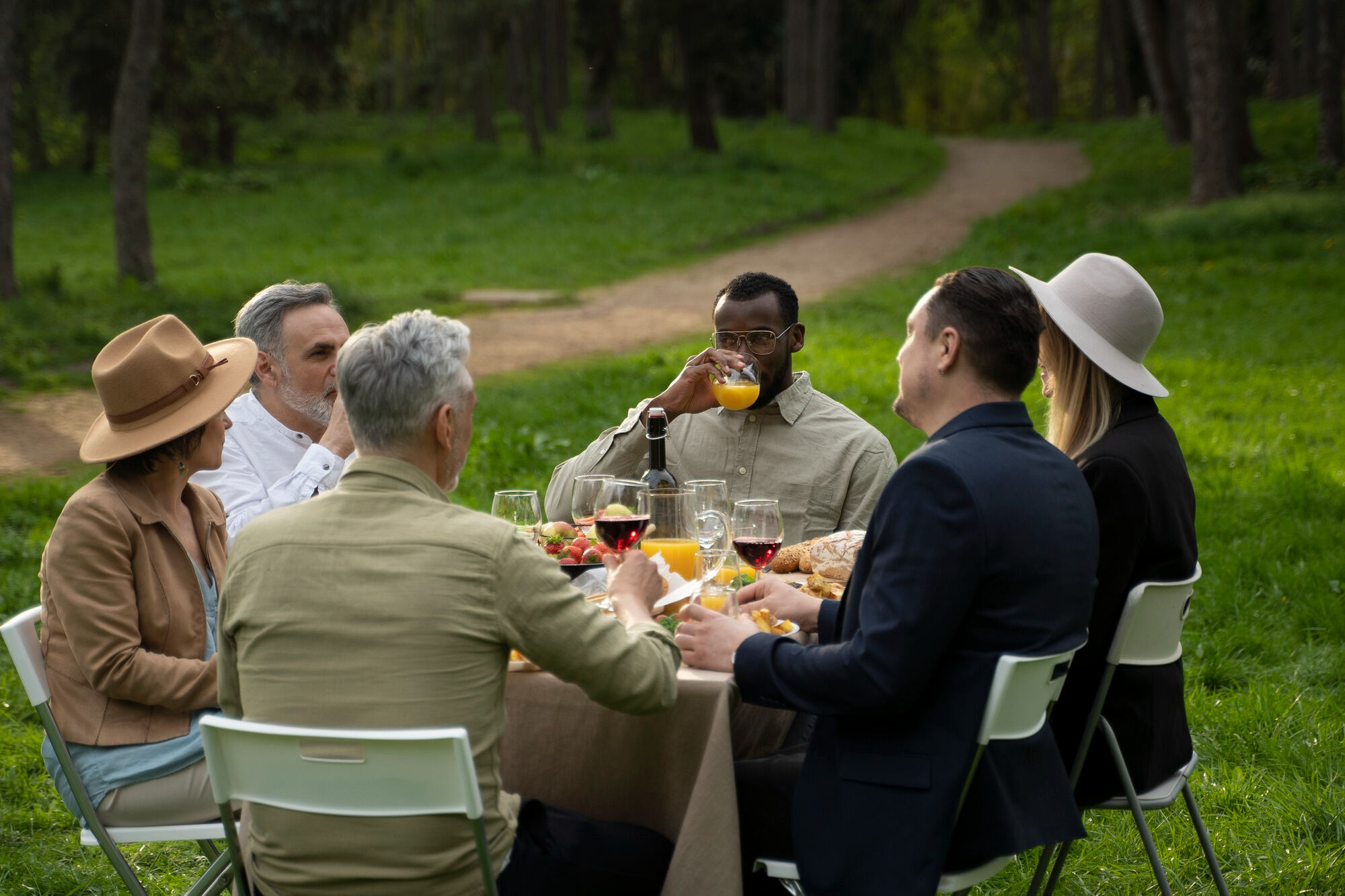 Grupo de amigos reunido em uma mesa ao ar livre, aproveitando um almoço juntos.